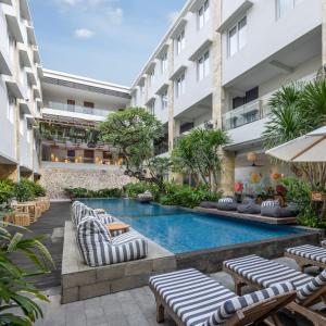 an image of a hotel with a pool and lounge chairs at Crystalkuta Hotel - Bali in Kuta