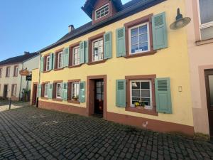 a yellow building with green shutters on a street at Wohlfühlen & Entdecken in der barocken Altstadt in Blieskastel
