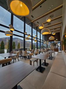 a restaurant with tables and chairs and large windows at Hotel IN in Žepče