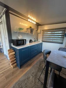a kitchen with blue cabinets and a table with a microwave at Stunning birch tree Lodge in Otley +19 photos