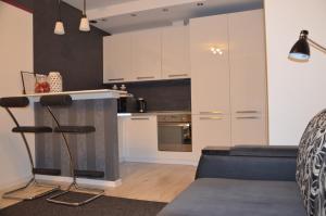 オルシュティンにあるApartamenty Szczęśliwe Snyの白いキャビネットと青いソファ付きのキッチンが備わります。