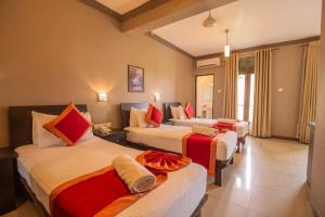 a hotel room with three beds with red and white at Kings Ridge Kandy in Kandy