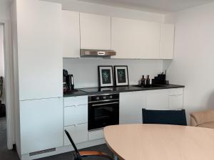 a small kitchen with white cabinets and a table at Comfort Apartment Midami in Schwanau +6 photos