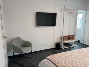 a bedroom with a chair and a television on the wall at Comfort Apartment Midami in Schwanau