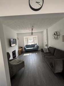a living room with a large clock on the wall at Craigport Cottage in Portrush