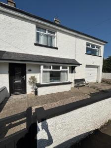 a white house with a bench in front of it at Craigport Cottage in Portrush