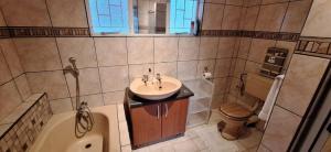 a bathroom with a sink and a tub and a toilet at Drakensberg Rest in Kimberley