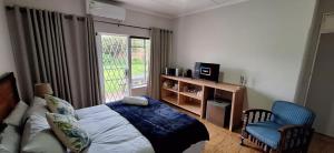 a bedroom with a bed and a chair and a window at Drakensberg Rest in Kimberley