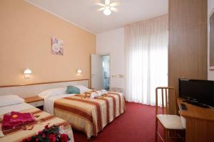 a hotel room with two beds and a flat screen tv at Villa Silvie Rose in Cesenatico