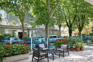 a patio with chairs and tables in front of a building at Villa Silvie Rose in Cesenatico