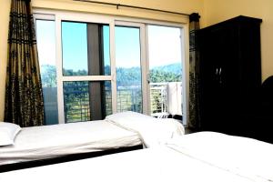 two beds in a room with a large window at Serenidad- The Cottage in Mukteshwar