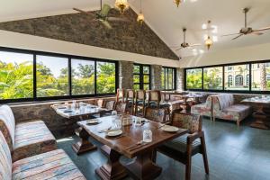 a restaurant with tables and chairs and large windows at Merriment Luxury Resort & Private Pool Villa Near Mount Abu, Abu Road in Bhīmānia