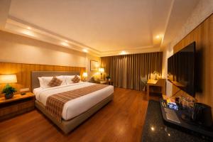 a hotel room with a bed and a flat screen tv at Pride Premier Darjeeling in Darjeeling