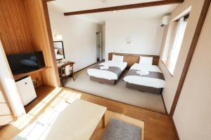 a hotel room with two beds and a flat screen tv at Hostel SAMURISE NORTH in Fujikawaguchiko