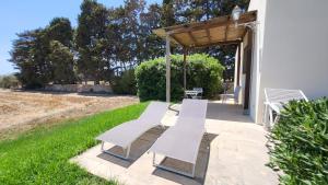a group of white benches sitting on a patio at Agriturismo Masseria sul Mare in Avola