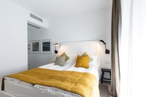 a bedroom with a white bed with yellow pillows at Seta Hotel in Bellagio