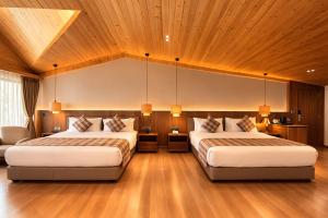 two beds in a room with wooden ceilings at Pride Premier Darjeeling in Darjeeling