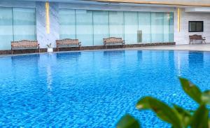 a large swimming pool with benches in a building at Enrich Grand Hotel in Bangkok