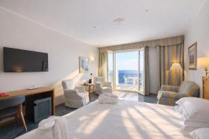 a hotel room with a bed and a desk and a television at LVG Hotel Collection - Grand Hotel Mediterranee in Alassio