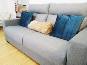a couch with two blue pillows and a blanket at LA CASINA DE HUGO AZUL centro Luanco in Luanco