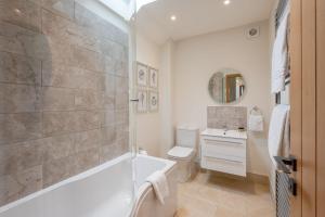 a bathroom with a tub and a toilet and a sink at Ellesmere Barn in Bedale +19 photos