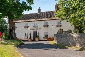 a white building with a tree in front of it at Ellesmere Barn in Bedale