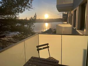 a bench on the balcony of a house with the sunset at Ruppiner Seeblick Ferienwohnungen in Neuruppin +8 photos