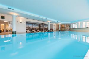 a large swimming pool with chairs in a building at Romantik Hotel Fischerwiege in Ahrenshoop