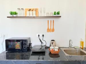 a kitchen counter with a microwave and a sink at 1BHK Suite with Balcony and Pool View in Noida +4 photos