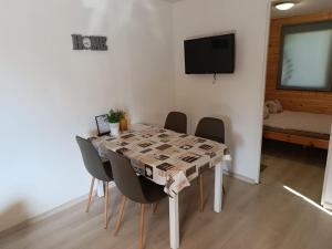 a dining room table with chairs and a television at Anna Ház in Balatonfenyves