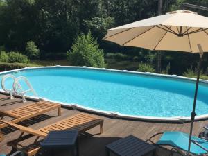 a swimming pool with chairs and an umbrella at Les Glycines Gîtes - Les Petites Pierres gîte - shared solar heated pool - garden spa - small dogs welcome in Vernoux-en-Gâtine