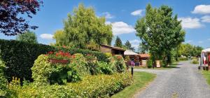 a garden with a hedge with flowers and a house at Le Pont Rouge & Les Vignes in Chipilly