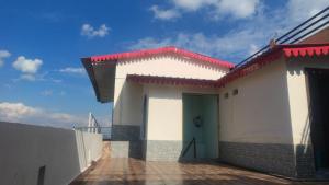 a white building with a red roof and a blue door at VAIBHAV VILAs in Gangolihāt