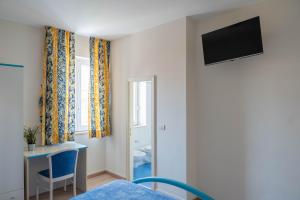 a room with a bed and a desk and a television at Hotel Centrale in Pineto
