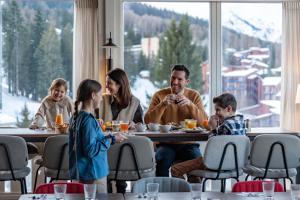 a family sitting at a table eating food at Belambra Clubs Arc 1800 - Hôtel Du Golf in Arc 1800