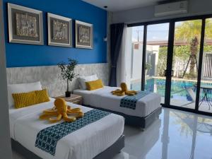 two beds in a room with a pool at Baan Yamoo Ranong in Ranong