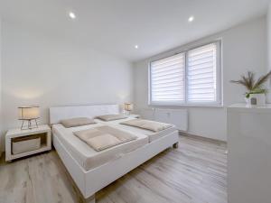 a white bedroom with a large bed and a window at Apartmán/byt Liptovský Mikuláš in Liptovský Mikuláš