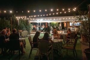 a group of people sitting at tables in a restaurant at night at Tenuta Moriano in Montespertoli