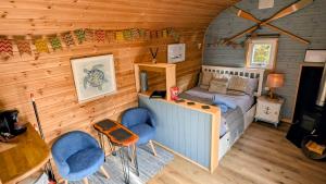 a room with a bed and chairs in a cabin at Emlyn's Coppice - Luxury Woodland Glamping in Holywell