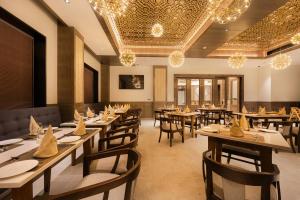 a restaurant with wooden tables and chairs and chandeliers at Ananta Express, Katra in Katra