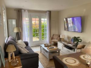 a living room with a couch and a tv at Villa Les Sables in Condette