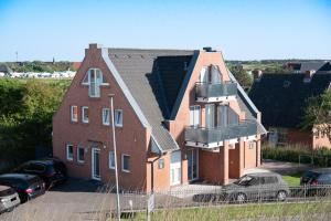a large brick house with cars parked in a parking lot at Haus-Eriel-EG-rechts in Brösum