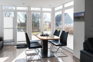 a dining room with a table and chairs and windows at Haus-Eriel-EG-rechts in Brösum