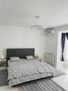 a white bedroom with a bed and a white wall at Apartamente CASA MIRIAM in Lugoj