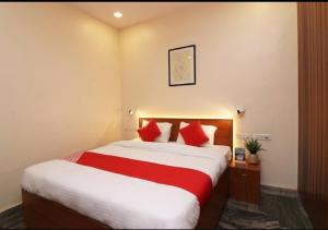 a hotel room with a large bed with red pillows at Hotel Meerut International in Meerut