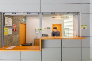a man standing at a counter in an office at Hi Espinho - Pousada de Juventude in Espinho