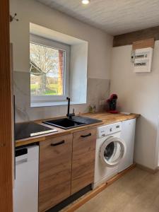 a kitchen with a sink and a washing machine at Le gîte de la courte soupe in Éteignières