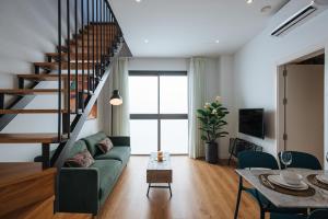 a living room with a green couch and a staircase at Alameda 1851 - Private jacuzzi in Seville