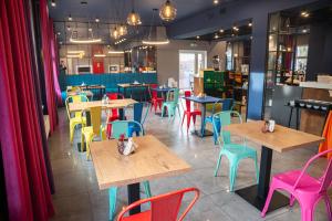 a restaurant with wooden tables and colorful chairs at IND.U Apartamenty in Kołobrzeg