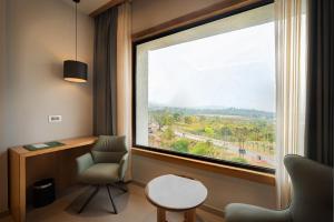 a room with a chair and a large window at Ananta Express, Katra in Katra